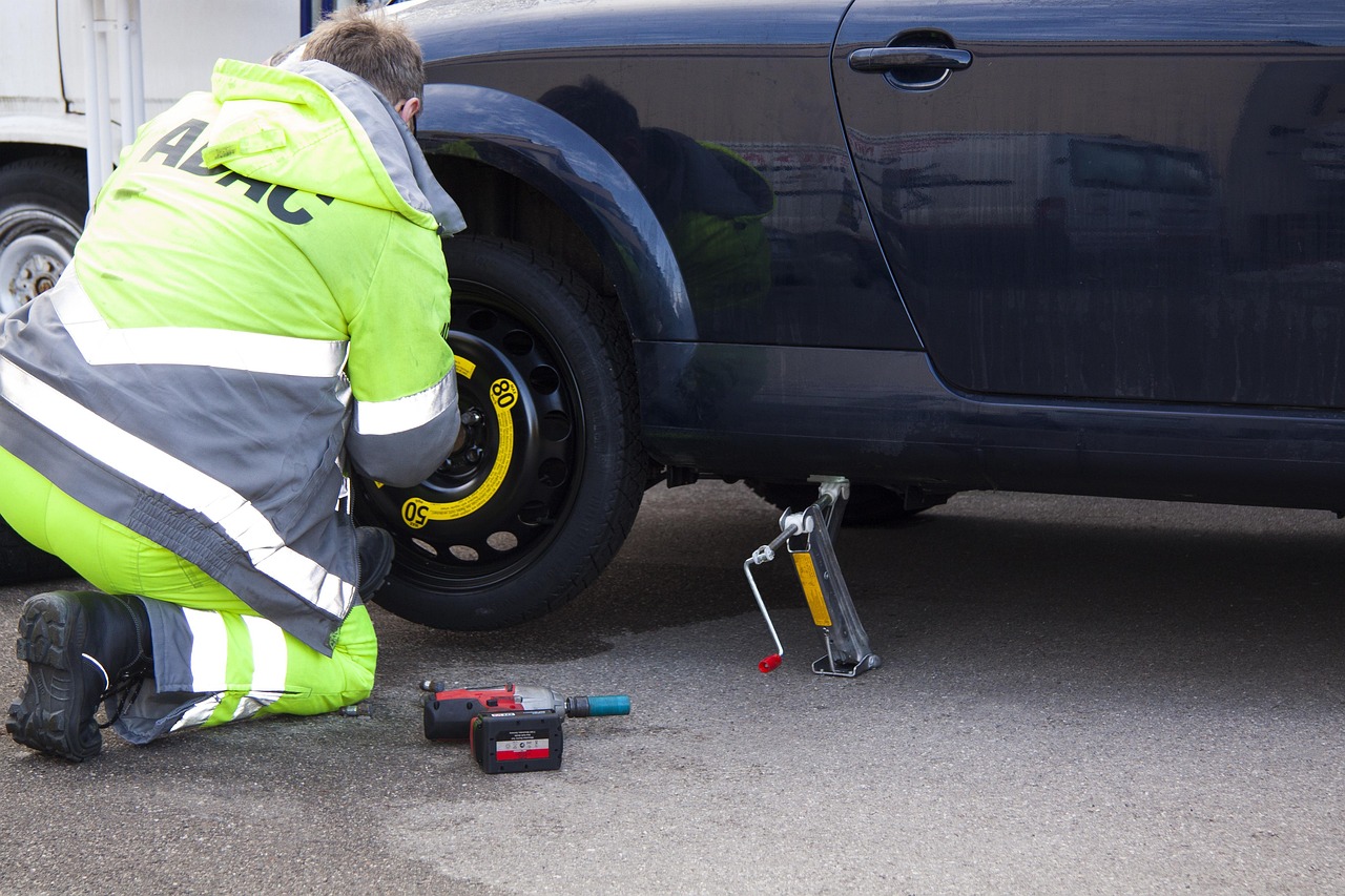 Roadside technician using a jack to change a car wheel