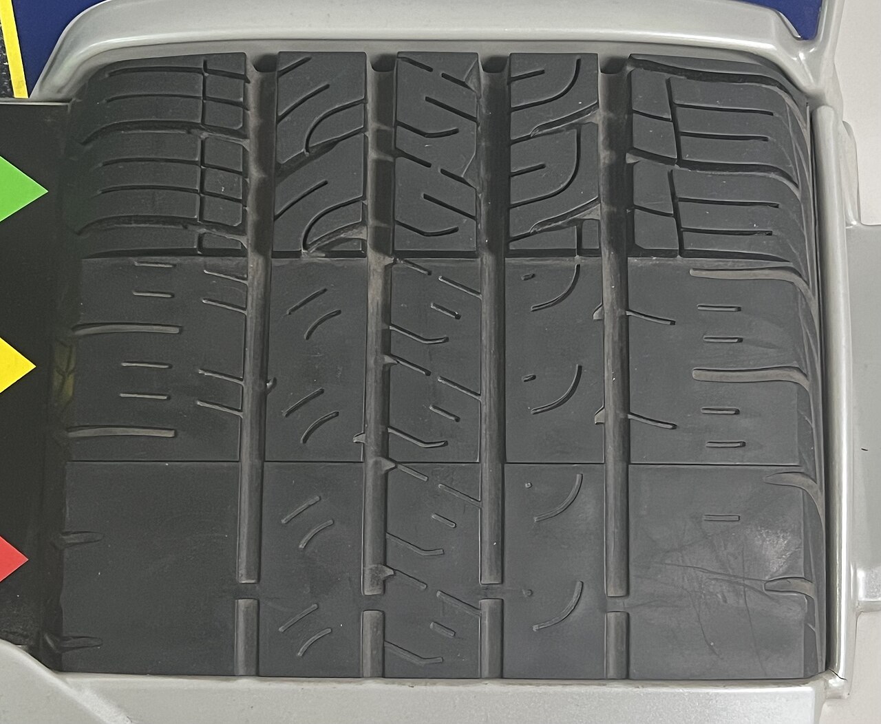 Close-up of worn tire tread showing uneven wear bars - exactly what a tread depth gauge measures